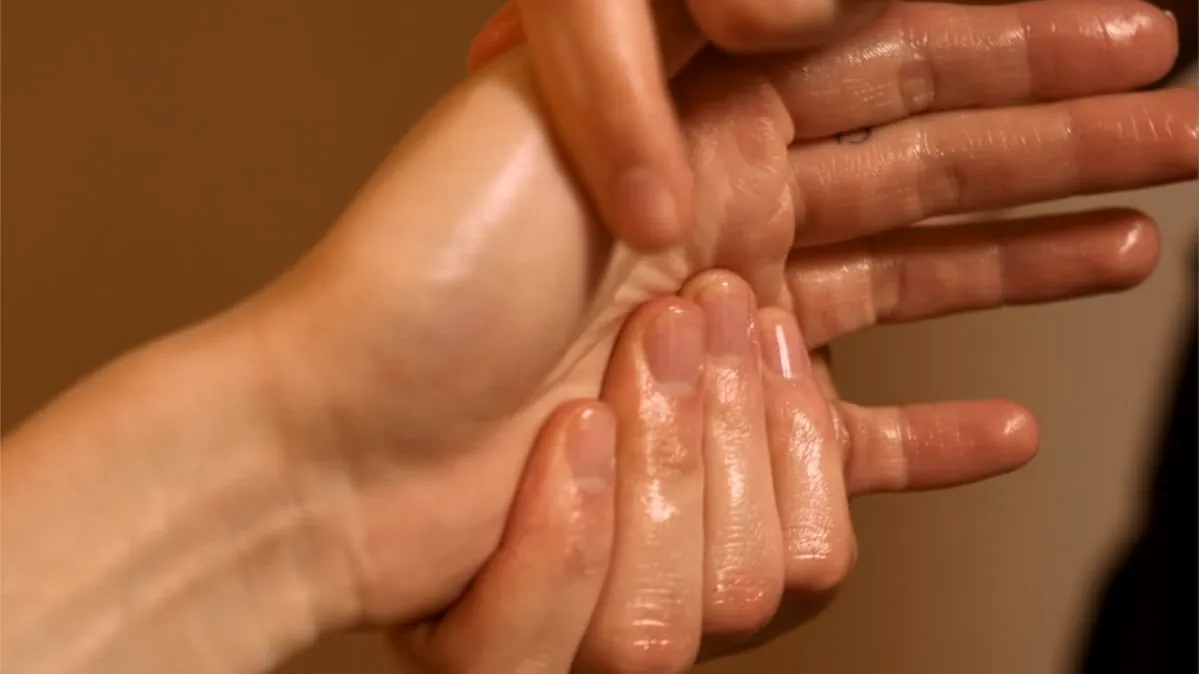 A Millán therapist massaging a client's hand and fingers with warm oil at Millán Spa, Miami Beach