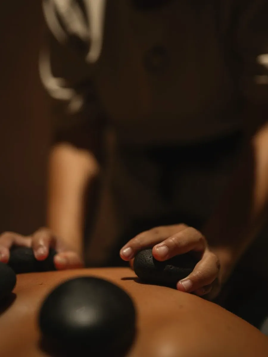 Hot stone massage: a Millán therapist placing warm stones along a client's back at the Miami Beach studio