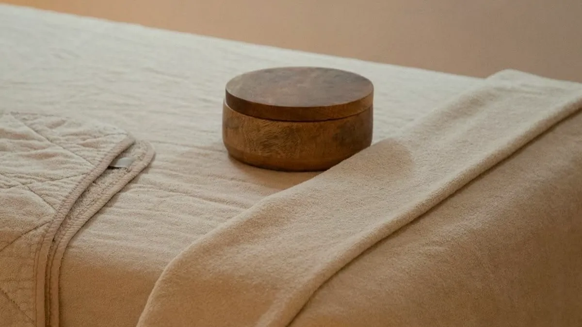 A massage table dressed in soft linen with a wooden bowl, set up for a Millán massage session