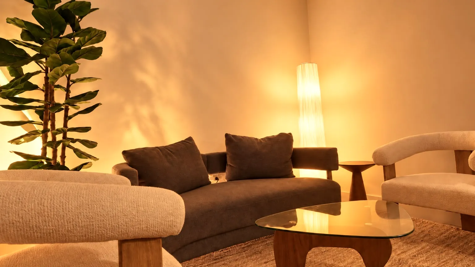 The Millán Spa lounge in Miami Beach: a grey sofa, cream armchairs, a fig tree and a paper floor lamp